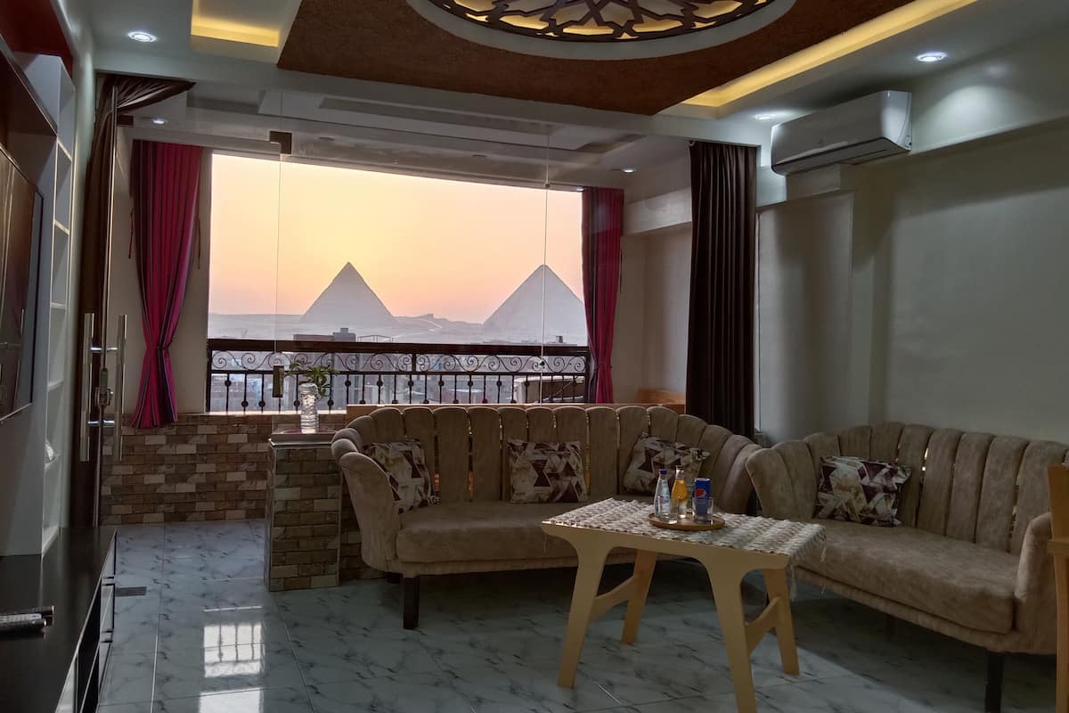A living room with a sofa, a small table, and a view of pyramids.