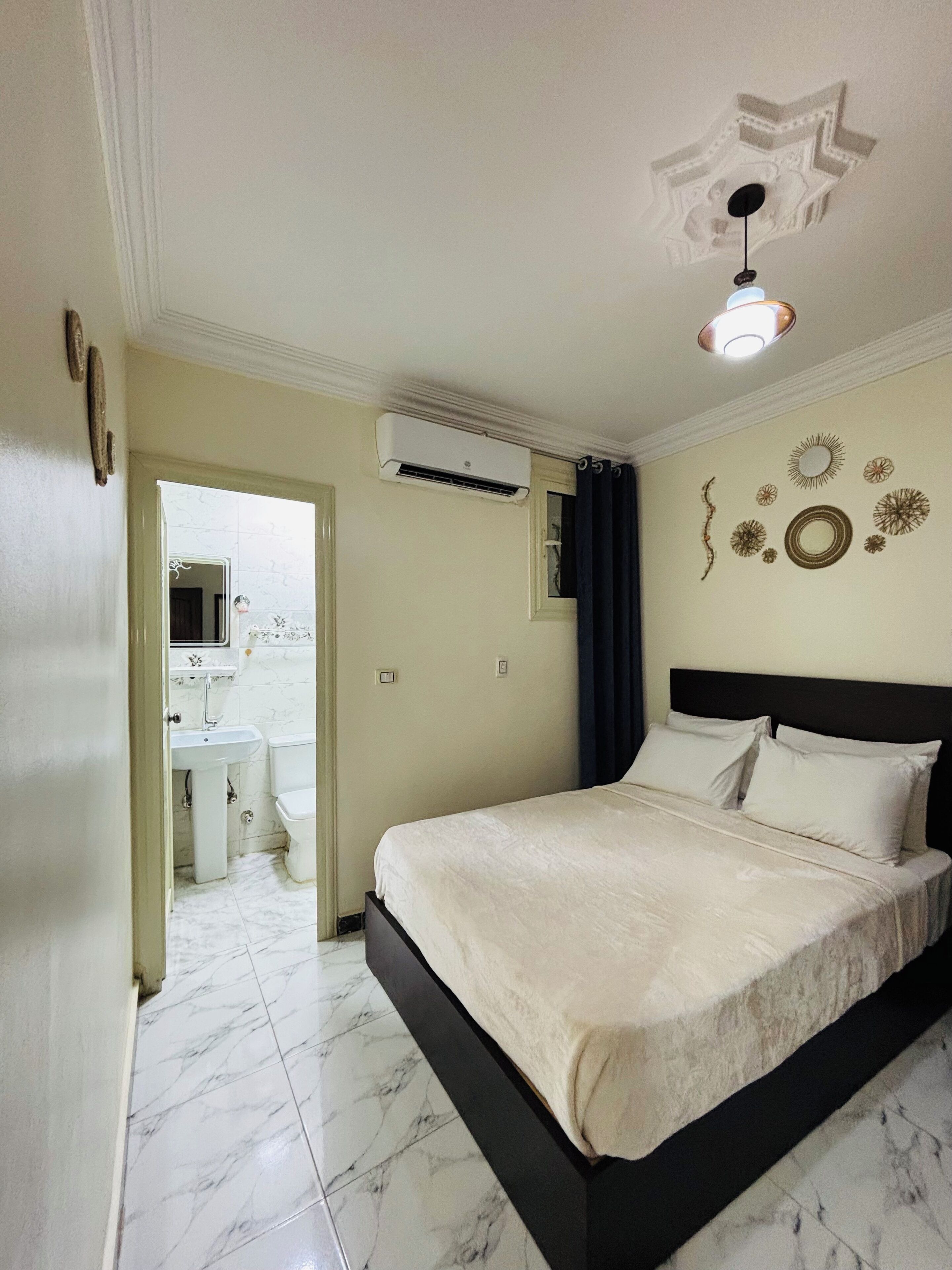 Une chambre d’hôtel comprenant un lit, une salle de bain avec un lavabo et des toilettes, et un appareil de climatisation.