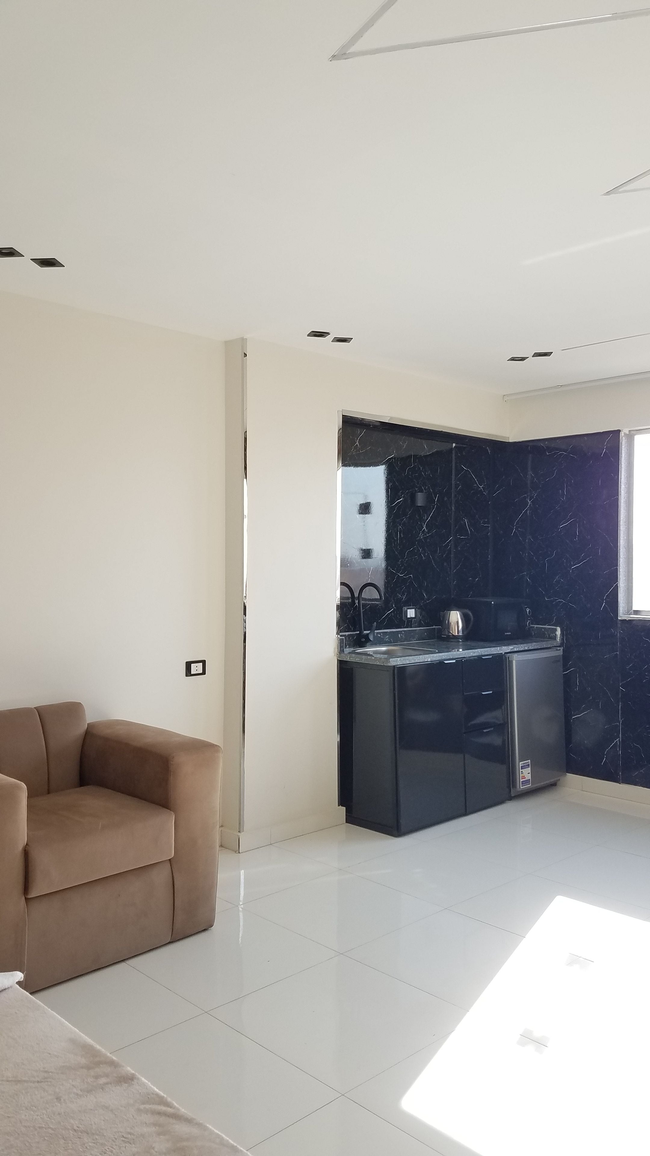 A modern kitchen with dark marble backsplash, a built-in oven, and a stainless steel refrigerator.