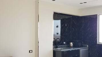 A modern kitchen with dark marble backsplash, a built-in oven, and a stainless steel refrigerator.