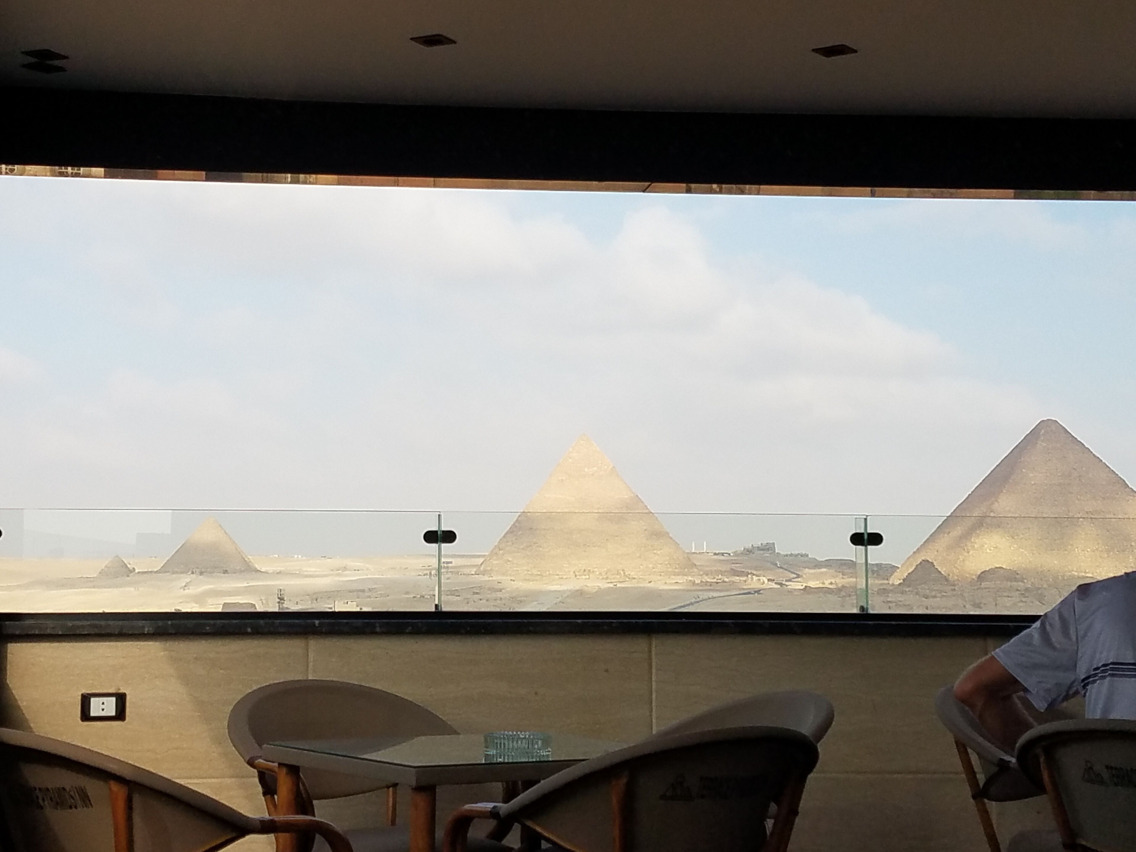 A view of the pyramids from inside a room with a table and chairs.