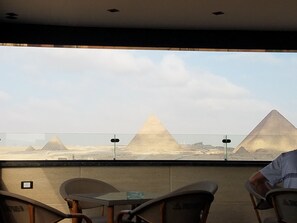 A view of the pyramids from inside a room with a table and chairs. - Pyramids Terrace INN (Giza)