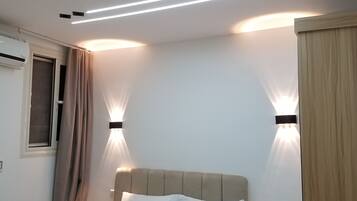Une chambre à coucher comprenant un lit, des lampes de chevet, une table de chevet et un climatiseur fixé au mur.