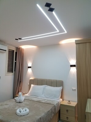 Een slaapkamer met een bed, nachtlampen, een nachtkastje en een wandairconditioner.