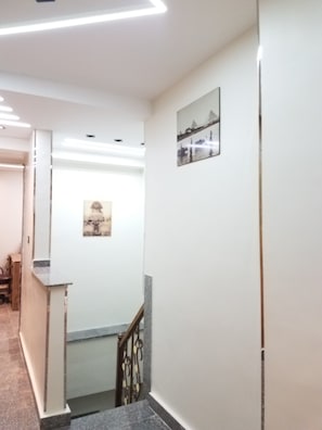 Un pasillo con una escalera, una recepción y un cuadro en la pared.