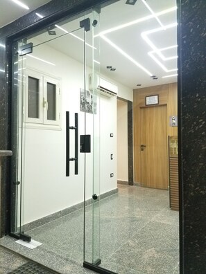 A modern interior with a glass door entrance, a wooden door, and a tiled floor. - Pyramids Terrace INN (Giza)