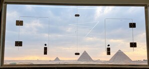 A window with a view of the pyramids and a clear sky. - Pyramids Terrace INN (Giza)