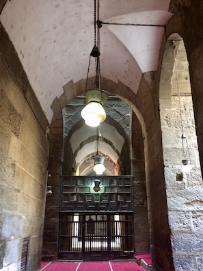 An arched stone corridor with hanging light fixtures and a central gate. - Pyramids Terrace INN (Giza)