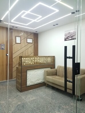A reception desk with a sign reading 'TERRACE PYRAMIDS INN' and a beige sofa in the background. - Pyramids Terrace INN (Giza)
