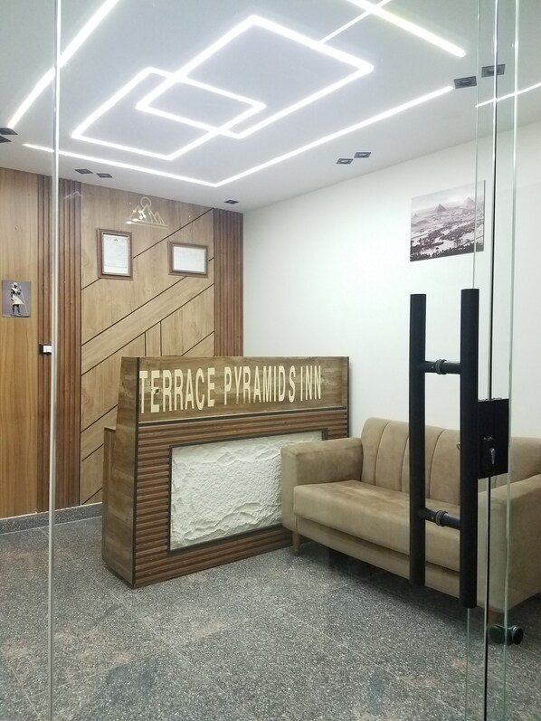 A reception desk with a sign reading 'TERRACE PYRAMIDS INN' and a beige sofa in the background. - Pyramids Terrace INN (Giza)