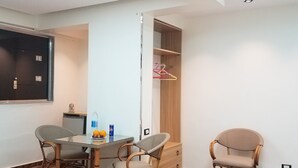 A hotel room with a dining table, two chairs, a bed with a white swan decoration, a wardrobe, and a TV mounted on the wall. - Pyramids Terrace INN (Giza)