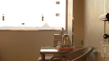 Una habitación con una mesa de comedor, sillas, una ventana con vistas a las pirámides y un estante con un llavero.