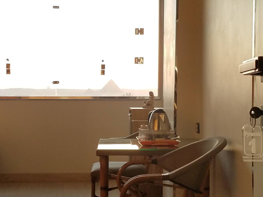 Une pièce comprenant une table à manger, des chaises, une fenêtre donnant sur les pyramides et une étagère murale sur laquelle est posé un porte-clés.