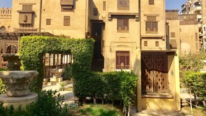 A traditional building with multiple windows and doors, surrounded by greenery and a stone fountain. - Pyramids Terrace INN (Giza)