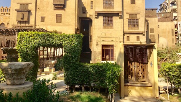 A traditional building with multiple windows and doors, surrounded by greenery and a stone fountain. - Pyramids Terrace INN (Giza)
