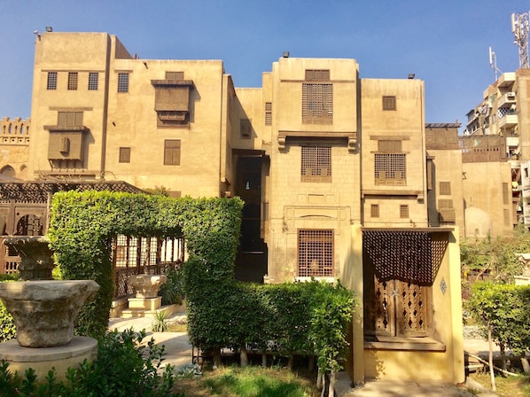 A traditional building with multiple windows and doors, surrounded by greenery and a stone fountain. - Pyramids Terrace INN (Giza)