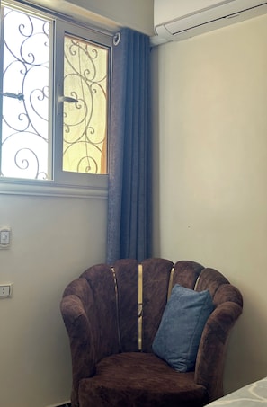 A corner room with a brown armchair, a window with decorative iron bars, and a curtain. - Pyramids Terrace INN (Giza)