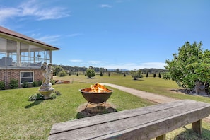 Un espace extérieur verdoyant, avec un barbecue, un banc en bois et une statue.