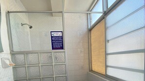 Ein Badezimmer mit Dusche, Waschbecken, Toilette und einem Fenster mit Aussicht.