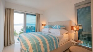 A bedroom with a bed, two bedside lamps, a small table, and a view of the outdoors. - Luxury villa Saga in Drvenik, private pool (Drvenik)