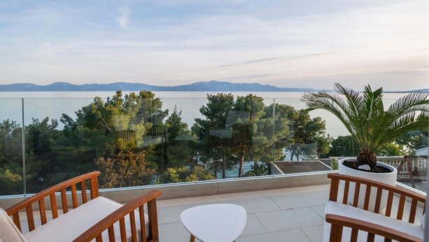 A balcony with a view of a lake and mountains, wooden furniture, and a potted plant. - Luxury villa Saga in Drvenik, private pool (Drvenik)