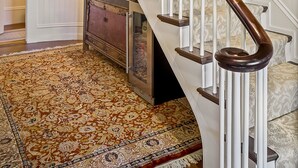 A staircase with white railings and dark wooden handrails, leading to a room with a patterned carpet and a dresser. - Abigail's Inn (Camden)