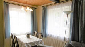 Un comedor con una mesa dispuesta para cuatro personas, un florero sobre la mesa y una silla en primer plano.