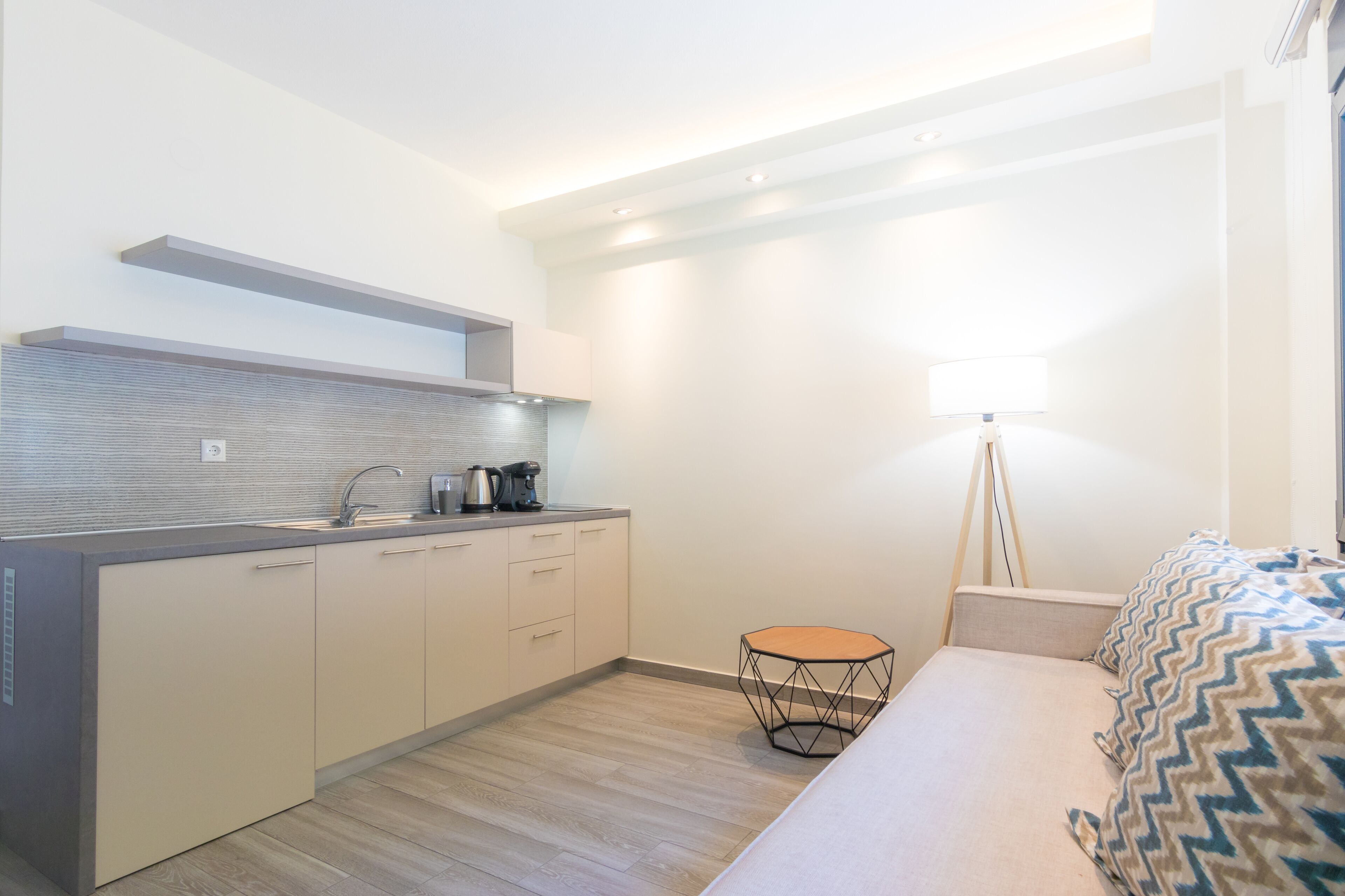 A compact kitchen with a modern design, a small round table, and a bed with patterned bedding.
