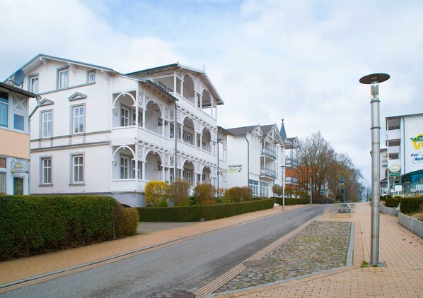 A street with a white building featuring a balcony and a sign reading "Tiefgarage".