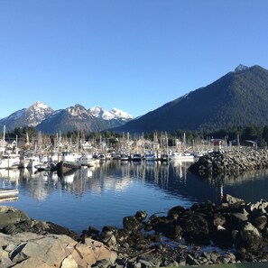 A marina with boats docked, surrounded by rocky shores and mountains in the background.