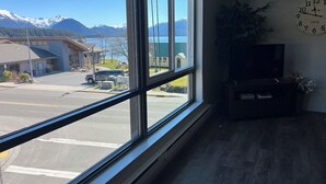 A room with a large window offering a view of a lake and mountains. - Downtown Apt. 5 w/ Ocean & Mountain Views. (Sitka)