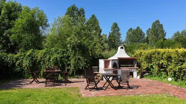 Zona de barbacoa al aire libre con parrilla, asientos y un camino de ladrillos.