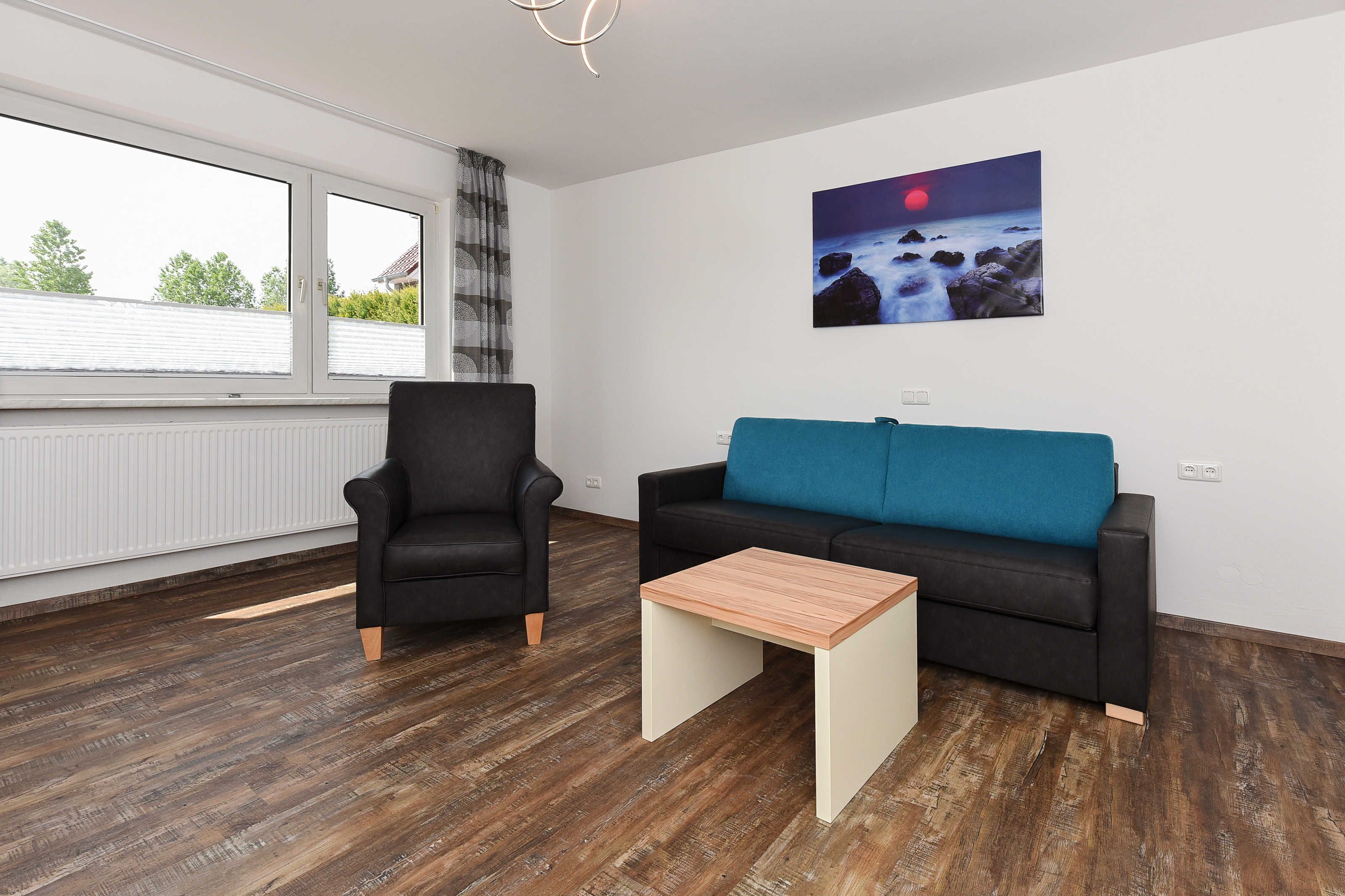 Una sala de estar moderna con un sillón negro, un sofá azul y una mesa de centro de madera.