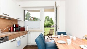Una cocina moderna con armarios blancos, encimera de madera y un comedor con mesa para cuatro.