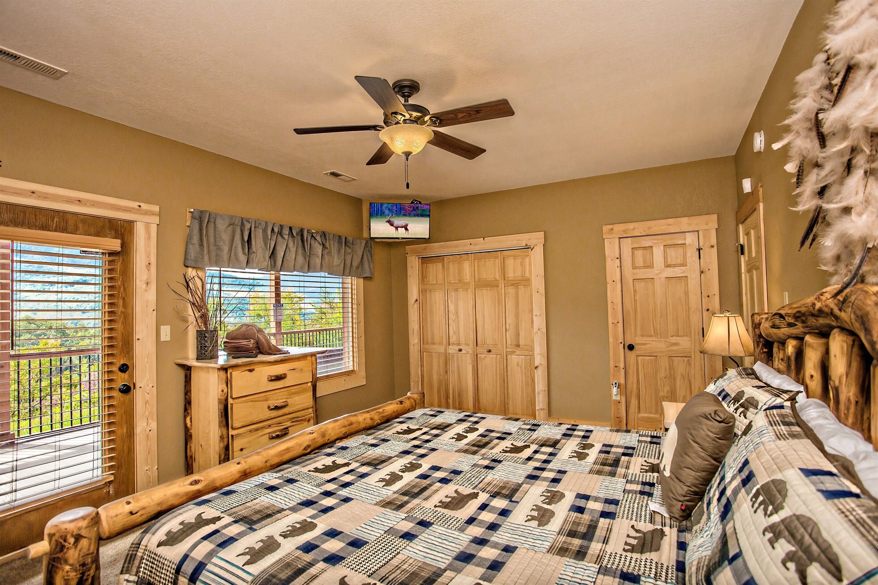 A bedroom with a large bed, wooden headboard, a ceiling fan, and a window with blinds.