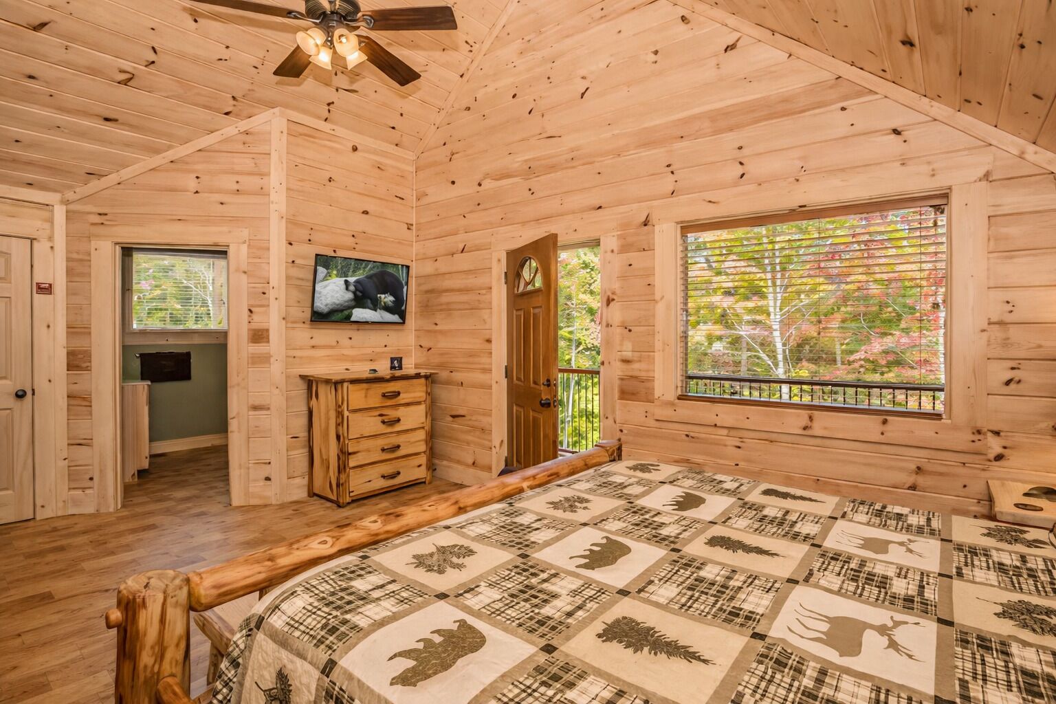 A log cabin bedroom with a bed, dresser, and a television on the wall.