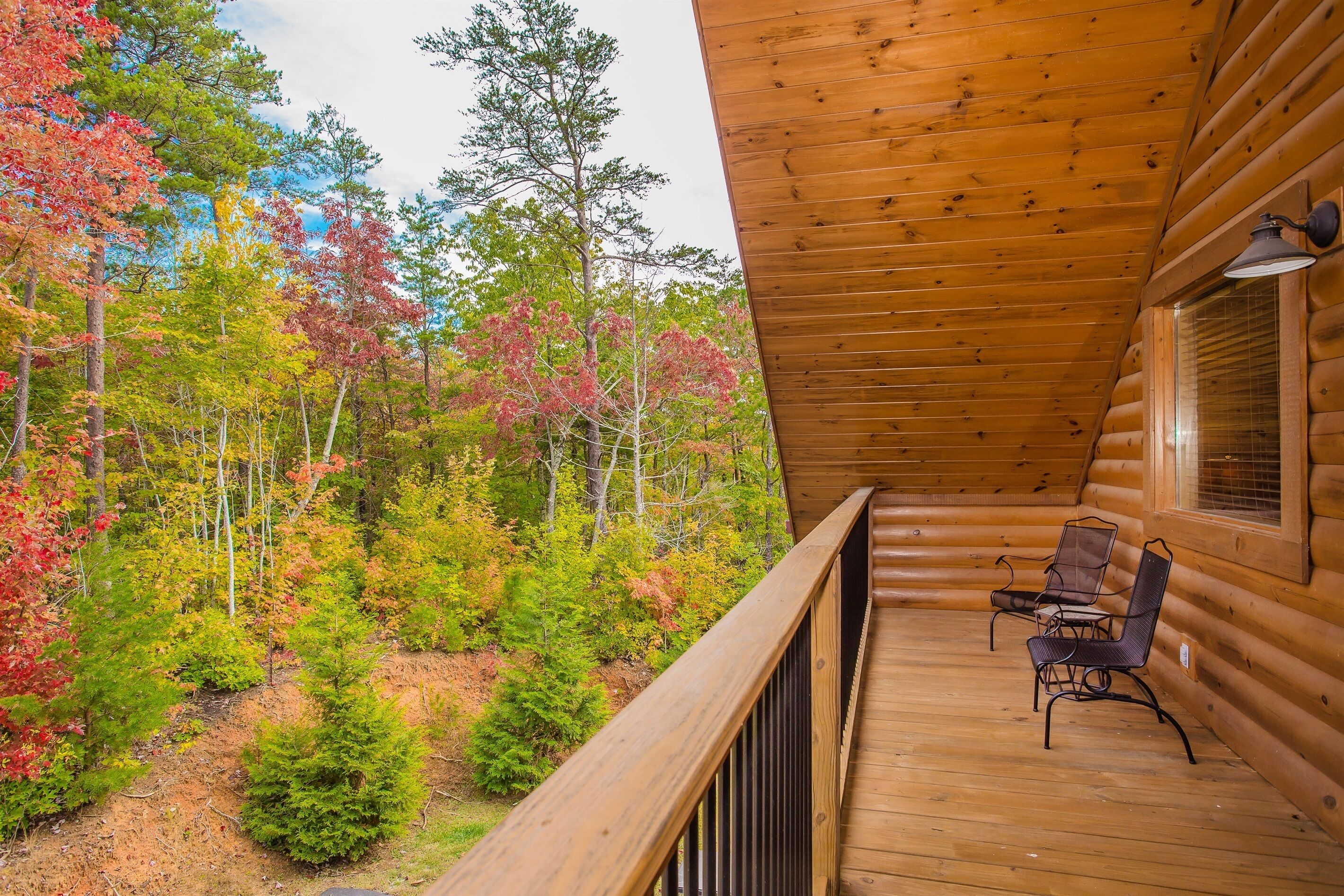 A wooden cabin with a balcony overlooking a forest.