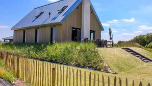 A modern building with a sloped roof, large windows, and a wooden fence. - Oesterdam Resort by Interhome (Tholen)