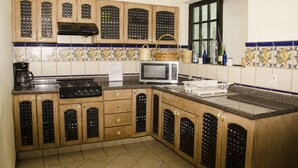 A kitchen with wooden cabinets, a microwave, a stove, and a window with a view. - Maria Bonita - Hostel (Guadalajara)