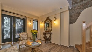 Ein Wohnzimmer mit einer Holztreppe, einem blumigen Sessel, einem runden Couchtisch mit Zeitschriften und einem Blumenstrauß.