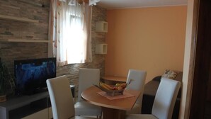 Un comedor con una mesa, sillas, un televisor y un frutero.