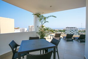 A balcony with a table and chairs, a potted plant, and a view of the cityscape. - Large Patio, Pool & Prime Location | 2BR Retreat (Puerto Vallarta)