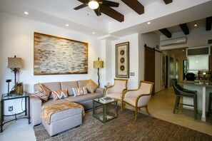 A living room with a sofa, armchairs, a coffee table, and a rug. There is a painting on the wall, a lamp, and a ceiling fan. - Large Patio, Pool & Prime Location | 2BR Retreat (Puerto Vallarta)