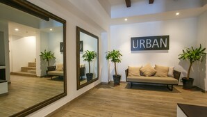 Una sala moderna con un espejo grande, un sofá y dos plantas en macetas.