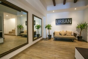 Een moderne woonkamer met een grote spiegel, een bank en twee potplanten.