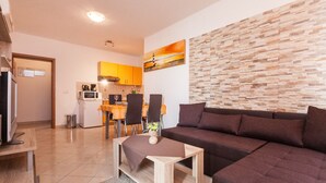 A modern living room with a sectional sofa, a coffee table, and a dining area with chairs and a table. - Apartments Jasmina (Rovinj)