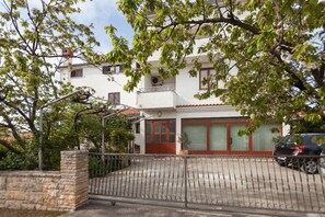A two-story residential building with a white facade, a red-tiled roof, and a gated driveway. - Apartments Jasmina (Rovinj)