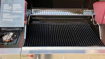 En Char-Broil-grill med en yta i rostfritt stål, en kontrollpanel och ett rött säte.