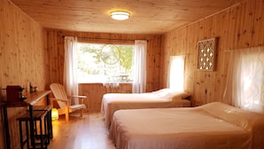 A wooden cabin room with two beds, a desk, and a chair. - Buddha Bing Cottage and Cabins (Northern Bruce Peninsula)