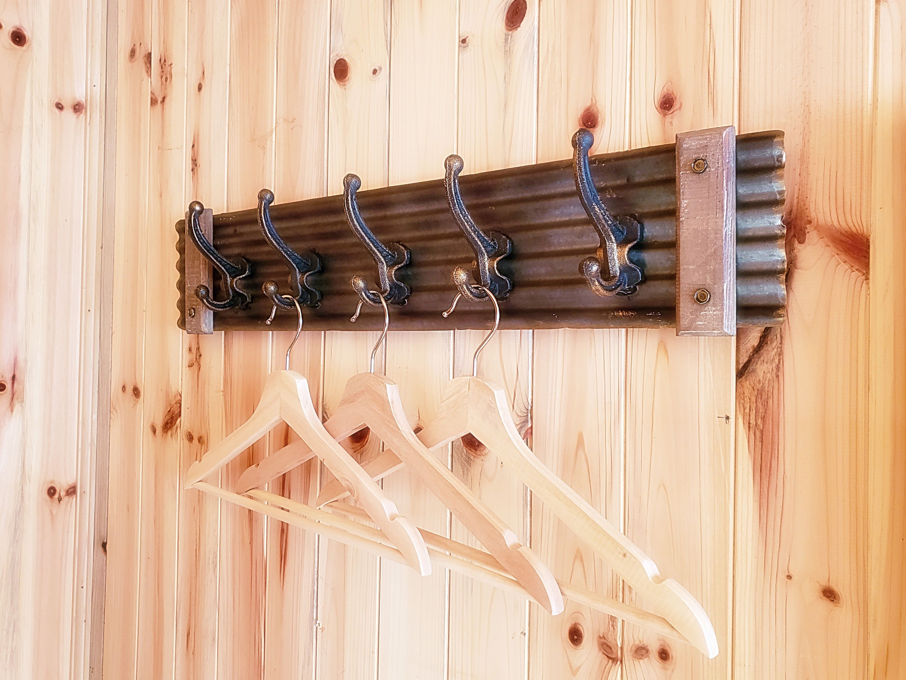 A wooden wall with a metal coat rack holding several wooden hangers.